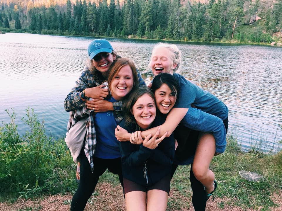 Camp Counselors hug in front of Eagle Lake.